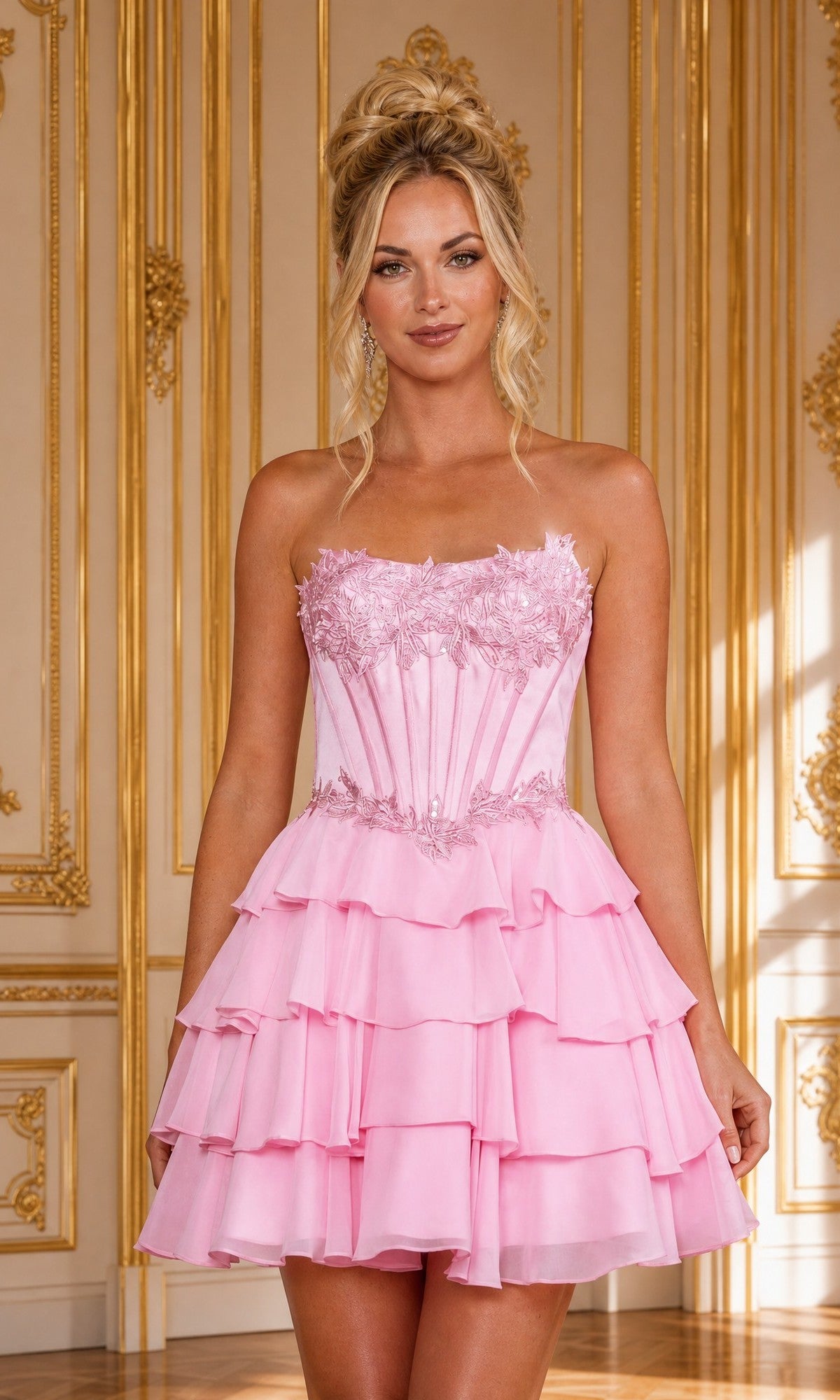 A woman wearing the Poly USA 26170 Lace-Up Ruffled Mini Hoco Dress in pink stands in an ornate gold-trimmed room, looking at the camera.